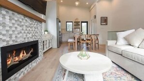 Un salon avec une cheminée, un coin repas et un canapé blanc.