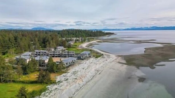 Une propriété située sur la côte, comprenant plusieurs bâtiments, une plage et une zone boisée.