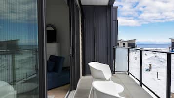 Ein Balkon mit Blick auf eine verschneite Landschaft, ein blaues Sofa und ein weißer Sessel.