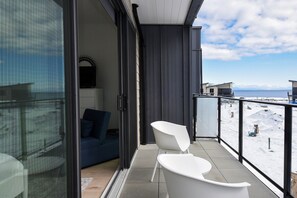 A balcony with a view of a snowy landscape, a blue sofa, and a white chair.