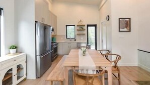 Une cuisine moderne avec une table à manger en bois, des chaises et un réfrigérateur.