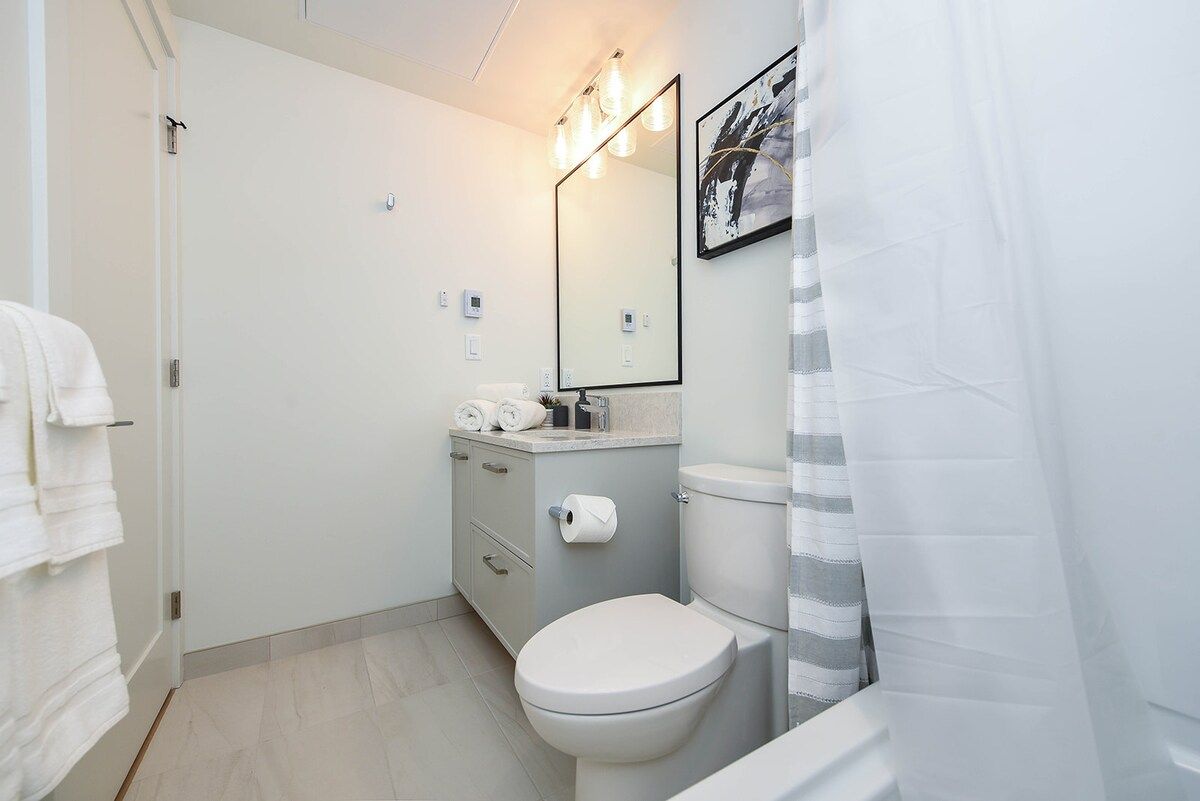 Ein Badezimmer mit Toilette, Waschbecken mit Spiegel und Duschvorhang.