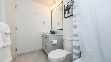 Ein Badezimmer mit Toilette, Waschbecken mit Spiegel und Duschvorhang.