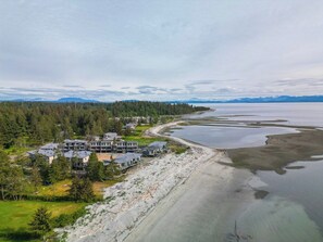 A coastal property with multiple buildings, a sandy beach, and a large body of water.