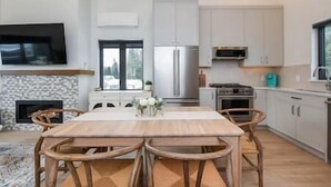 Une cuisine moderne avec un coin repas, comprenant un grand réfrigérateur, un four à micro-ondes, un four traditionnel et un téléviseur à écran plat fixé au-dessus de la cheminée.