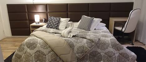 A neatly made bed with patterned bedding, a headboard, and a bedside table with a lamp.