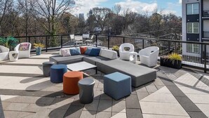 Un patio al aire libre con un sofá seccional, sillones, otomanas y una mesa de comedor.
