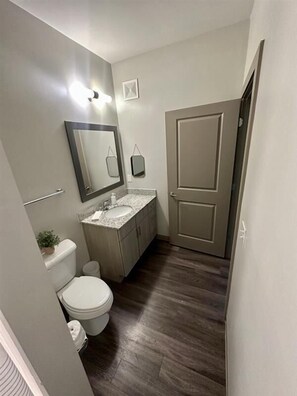 A compact bathroom with a toilet, sink, and mirror. - Midtown Atlanta Apt: Pool, Garage, 4 Bedrooms! (Atlanta)