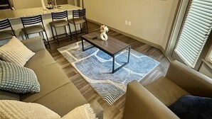 Una sala de estar moderna con un sofá, una mesita de centro y un televisor de pantalla plana montado en la pared.