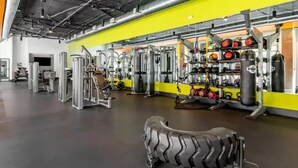 Un gimnasio con varios equipos de ejercicio, que incluyen máquinas de pesas, pesas sueltas y un saco de boxeo.