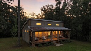 A wooden cabin with a porch and a covered deck, surrounded by trees. - Sea Cow Retreat - Near Springs + Porch, Covered Deck & Fire Pit (Crystal River)