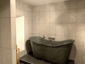 A modern bathroom with a freestanding bathtub, tiled walls, and a wooden bench. - Le Moulinage Chabriol - The Loft (Saint-Pierreville)