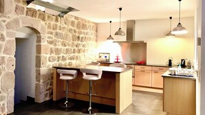 Uma cozinha com parede de pedra, armários de madeira e dois banquetas.