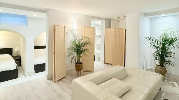 A modern bedroom with a large bed, a sofa, and a walk-in closet.