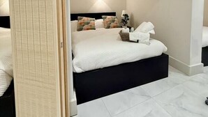 A modern bedroom with a large bed, a bedside table, a nightstand, and a wall-mounted light.