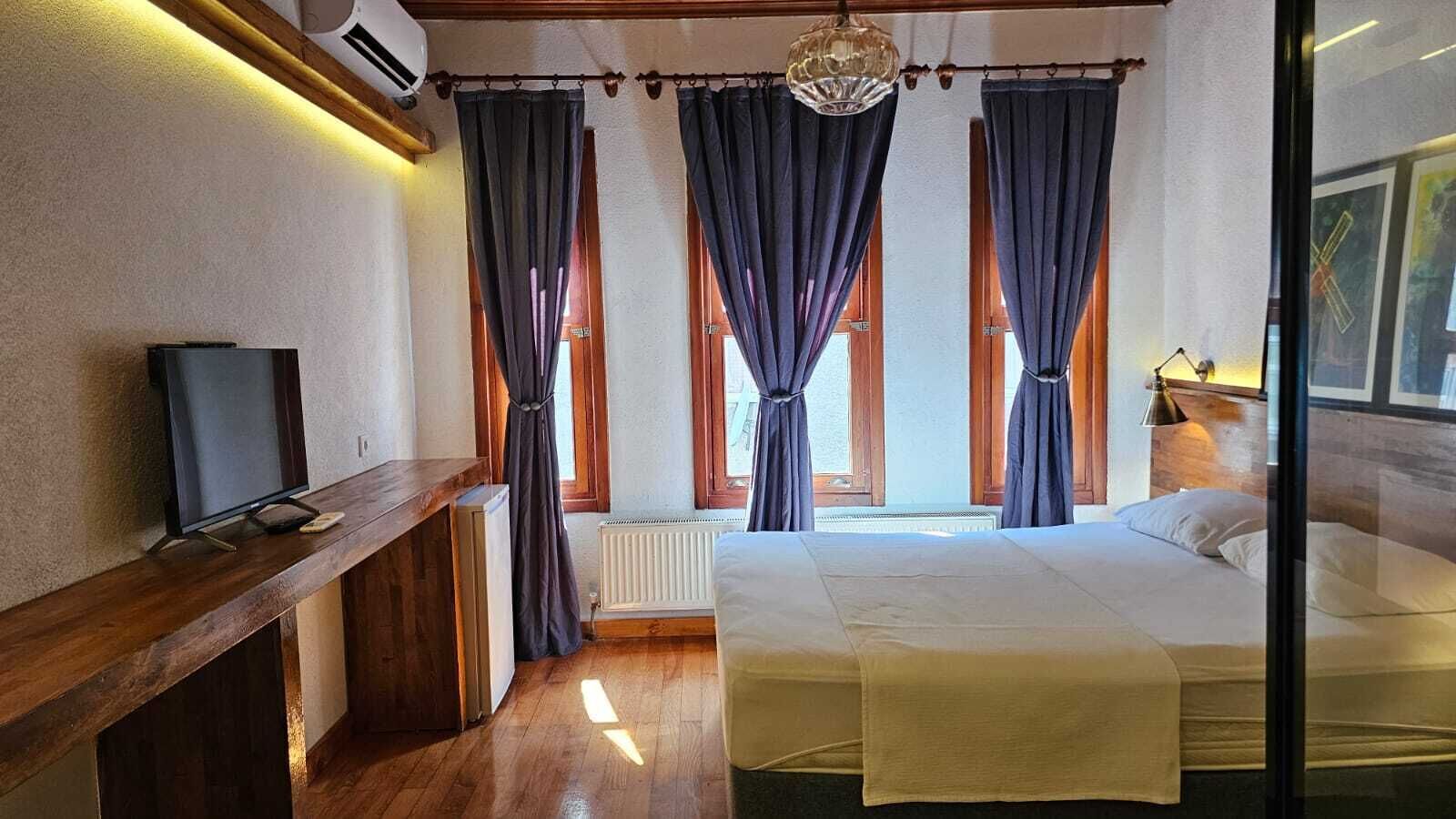 Ein Schlafzimmer mit einem Bett, einem Fernseher, einem Heizkörper und Vorhängen.