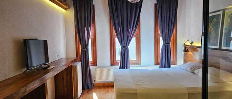 Ein Schlafzimmer mit einem Bett, einem Fernseher, einem Heizkörper und Vorhängen.