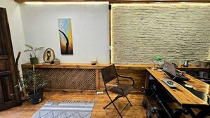 A cozy reception area with a wooden desk, a chair, a laptop, and a rustic stone wall. - Mahzen Otel (Istanbul)