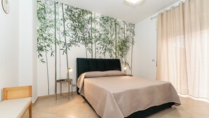 A bedroom with a bed, bedside table, and a chair. - Elegant apartment (Catania)