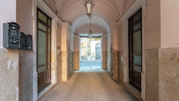 A hallway with a herringbone floor, double doors, and a hanging light fixture. - Elegant apartment (Catania)