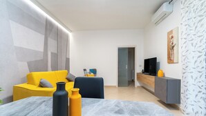 A modern living room with a yellow sofa, a grey couch, and a dining table with two vases. - Elegant apartment (Catania)