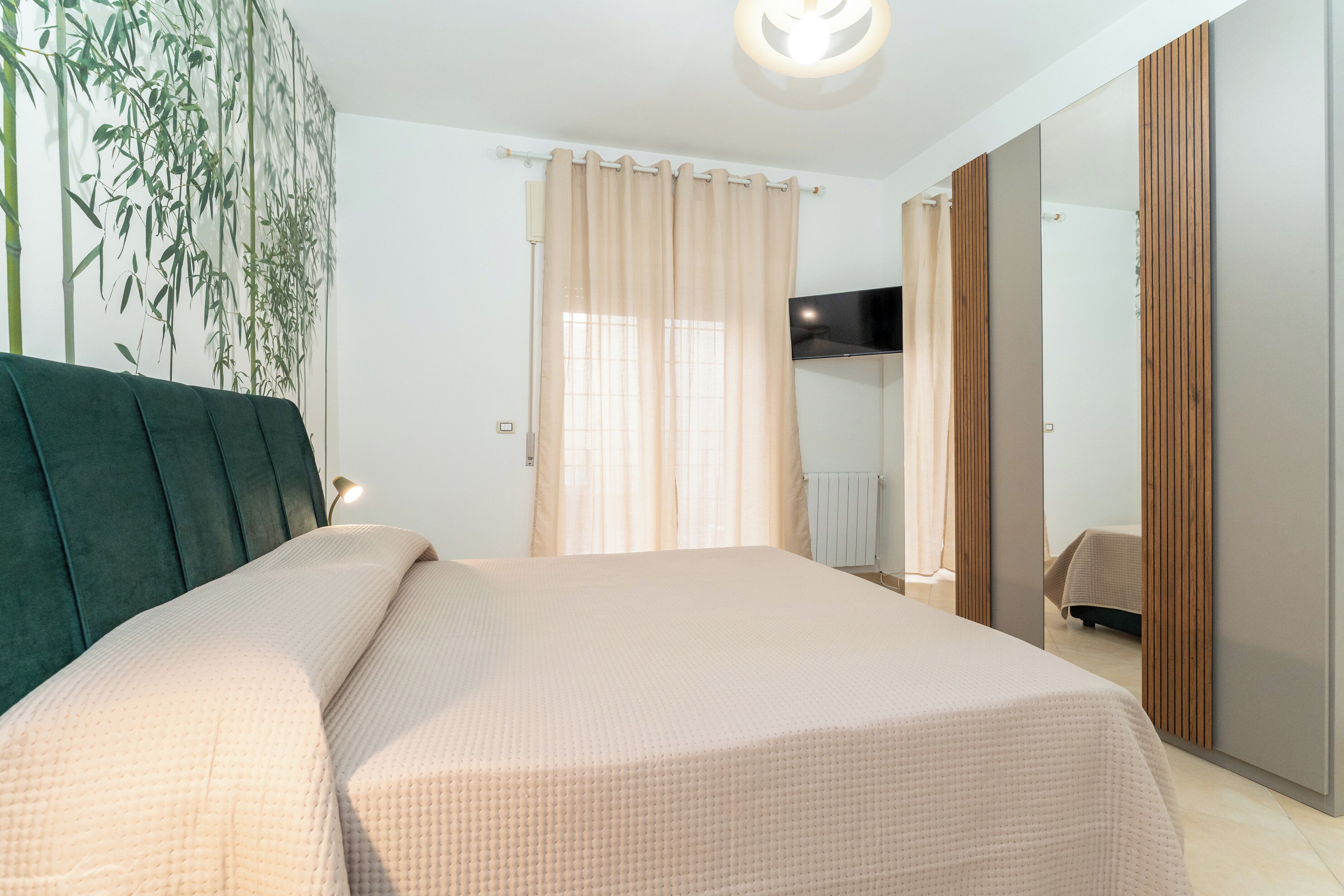 Ein modernes Schlafzimmer mit einem großen Bett, einem an der Wand montierten Fernseher und einem Spiegel.