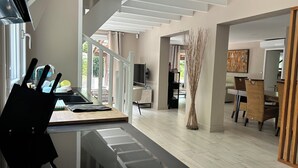 A modern interior with a kitchen area, dining space, and a staircase leading to an upper level. - Villa 17 pers with jacuzzi - Lacanau, lake & ocean, private estate (Lacanau)