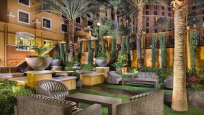 An indoor courtyard with seating areas, palm trees, and a staircase leading to an upper level. - Lovely Las Vegas 1BD Suite Near the Strip! (Las Vegas)