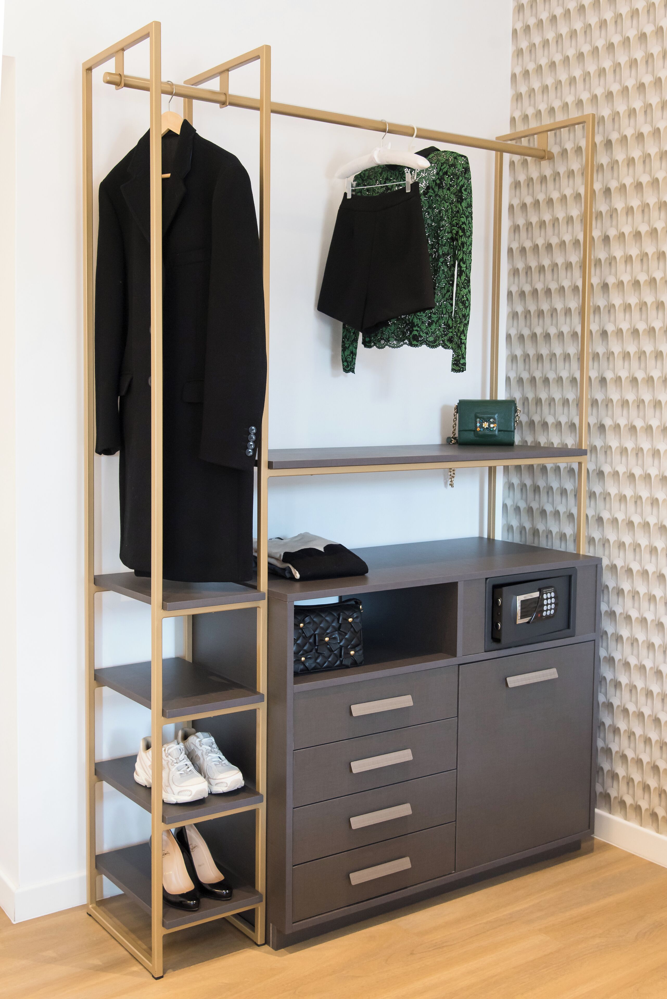 A modern wardrobe with multiple shelves and drawers, a hanging rack, and a small green bag on the top shelf.