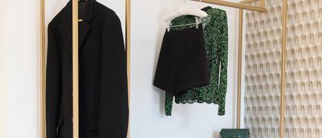 A modern wardrobe with multiple shelves and drawers, a hanging rack, and a small green bag on the top shelf.