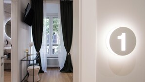 Ein modernes Badezimmer mit Toilette, einer Glasvitrine und einem großen Fenster mit Vorhängen.