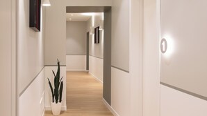 Ein moderner Flur mit Holzboden, weißen Wänden und eingelassener Beleuchtung.