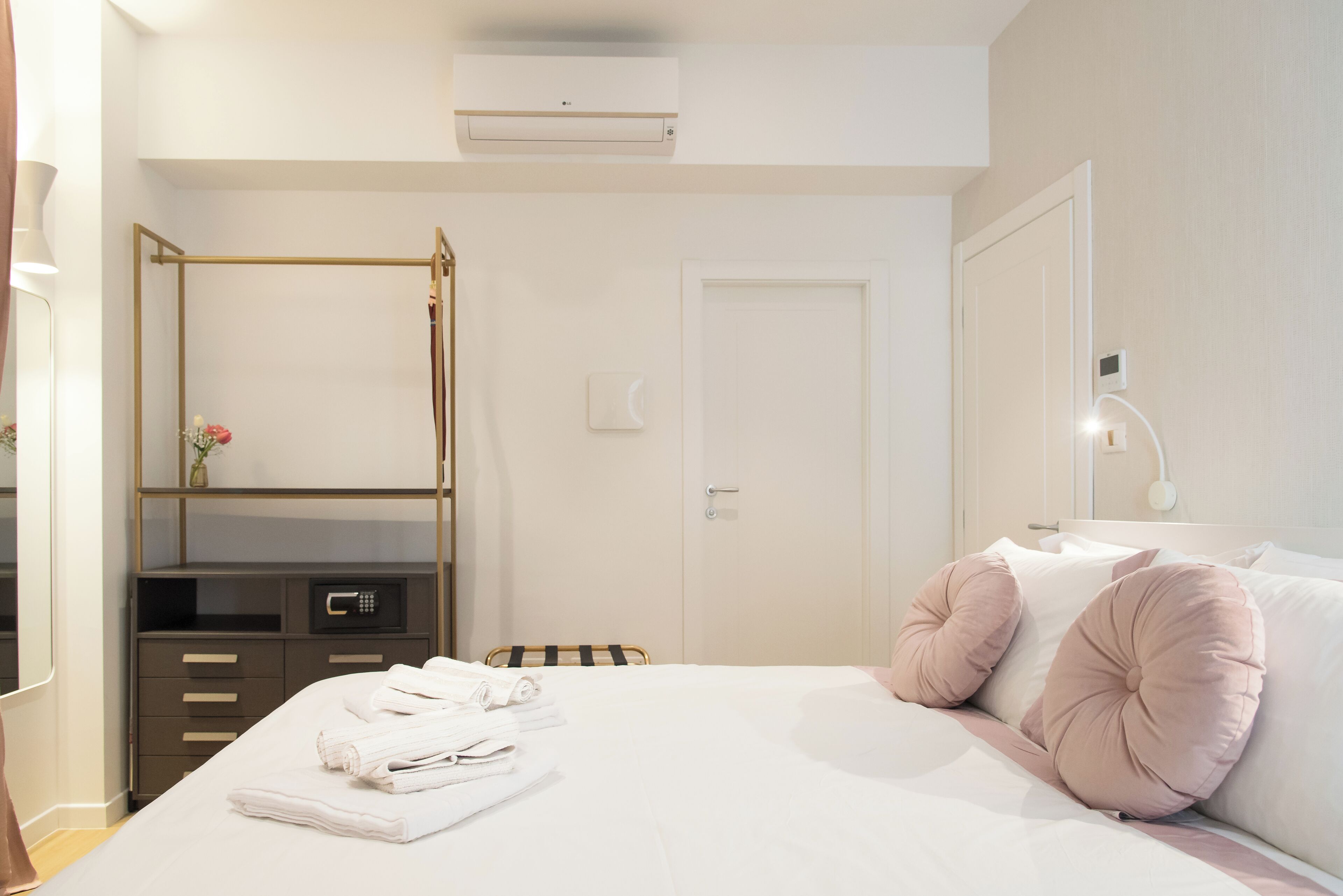 Ein Hotelzimmer mit Bett, Nachttisch, Spiegel, Kleiderschrank und Klimaanlage.