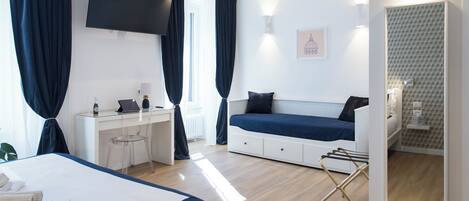 Et moderne hotelværelse med seng, skrivebord, siddeplads og fjernsyn.