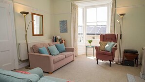 Un salon comprenant un canapé, un fauteuil, une lampe sur pied et donnant sur des panneaux solaires situés à l’extérieur.
