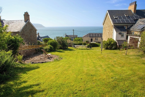 A coastal property with a grassy lawn, stone buildings, and a view of the sea.