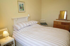 A bedroom with a bed, a nightstand, a dresser, a chair, and a painting on the wall. - Morfan, Tresaith - Four Bedroom Cottage, Sleeps 8 (Tresaith)