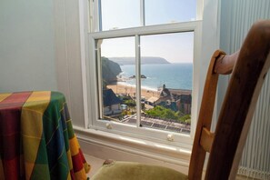 Una habitación con un ventanal que da a una playa y acantilados.