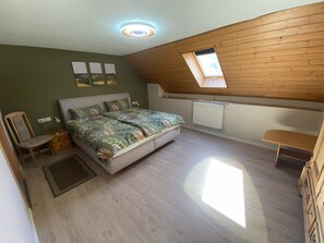 A bedroom with a sloped ceiling, a bed with floral bedding, a chair, a radiator, and a skylight. - Quiet living at the winegrower's with a view of the vineyards - own restaurant (Burgen)