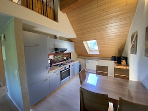 Et moderne køkken med ovenlys, træloft og et spiseområde med bord og stole.