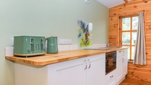 Een compacte keuken met een houten aanrecht, een groene toaster, een waterkoker en een spoelbak.