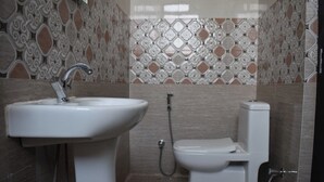 Ein Badezimmer mit Waschbecken, Toilette und Dusche. Die Wände sind mit dekorativen Fliesenmustern versehen.