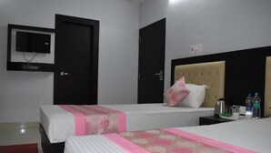 Ein Hotelzimmer mit zwei Betten, einem an der Wand befestigten Fernseher und einer Minibar.