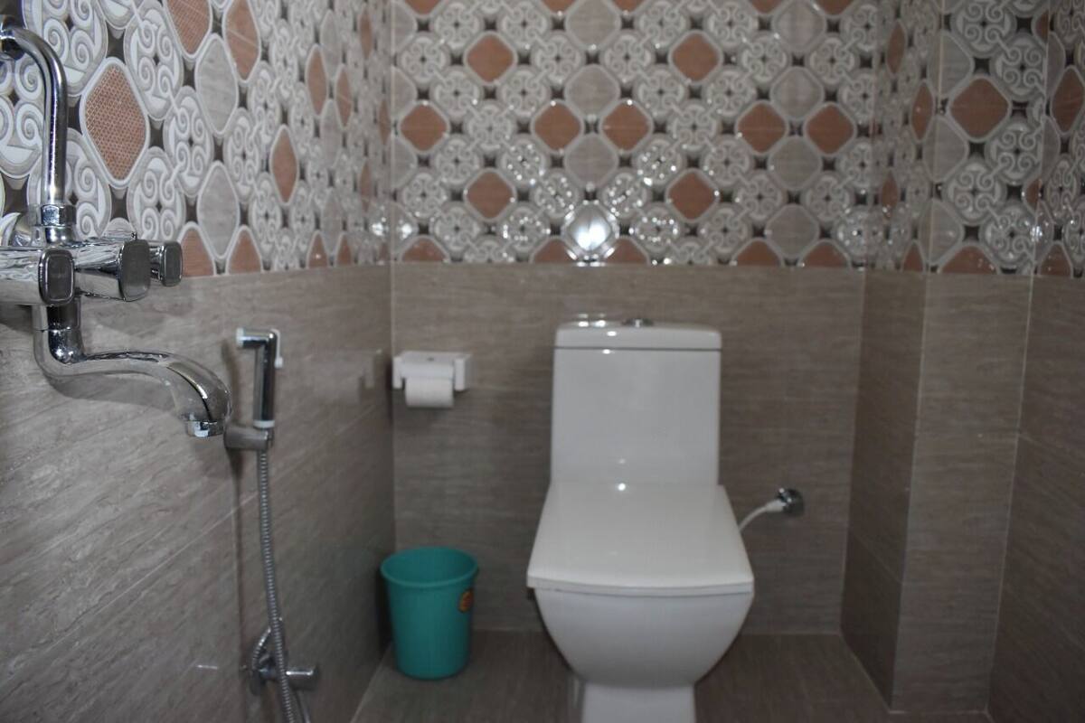 A bathroom with a toilet, a shower, and a wall with patterned tiles.