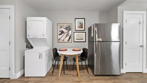 A compact kitchen with a washing machine, a refrigerator, and a dining table with chairs. - Optimist Abode 2: Chic Stay in the Queen City, walking distance to Optimist Hall (Charlotte)