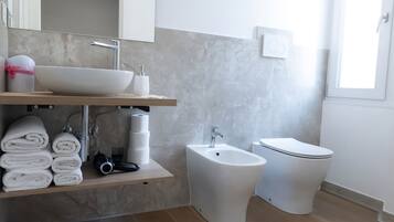 A modern bathroom with a sink, bidet, toilet, and a towel rack.
