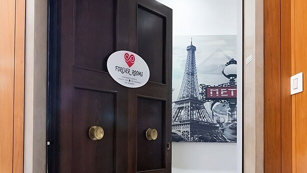 Une porte en bois sombre, sur laquelle est apposée une plaque portant l’inscription « Forever Rooms ».