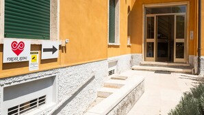Un bâtiment à la façade jaune, une enseigne indiquant « FOREVER ROOMS », et un escalier menant à une porte dotée de panneaux de verre.