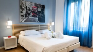 Un lit bien fait, avec du linge de lit blanc, une tête de lit à lattes horizontales, une table de chevet sur laquelle se trouve un objet rouge, un tableau représentant un autobus rouge accroché au mur, et une fenêtre avec des rideaux bleus.