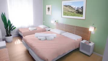 A hotel room with two beds, a potted plant, a framed picture, and a bedside table with a lamp.